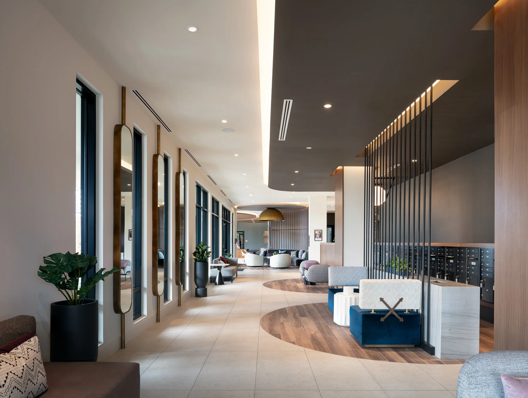 Modern hotel lobby with large windows, contemporary furniture, and decorative elements, featuring seating areas, plants, and stylish lighting.