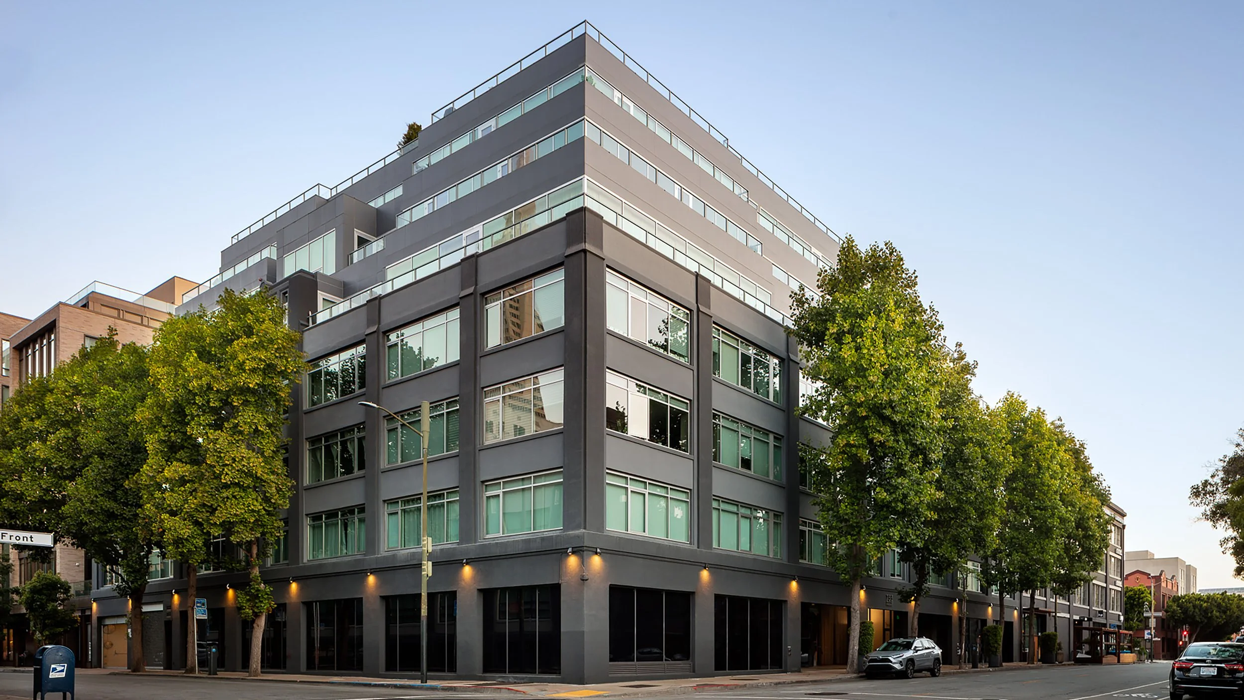 Modern multi-story building with large windows on a tree-lined city street.
