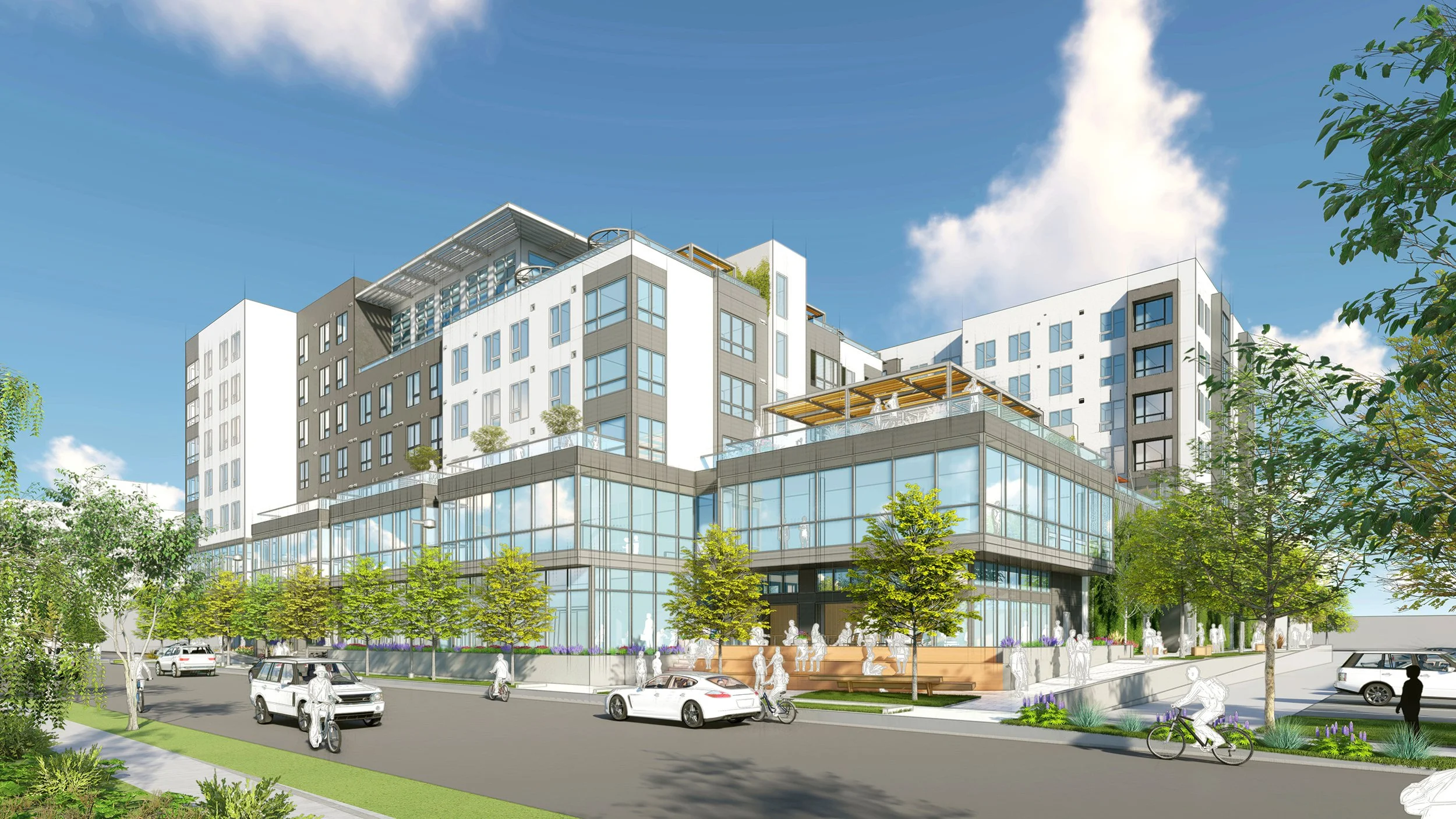 Modern multi-story commercial building with glass storefronts, trees, and parked cars on a street under a blue sky with clouds.