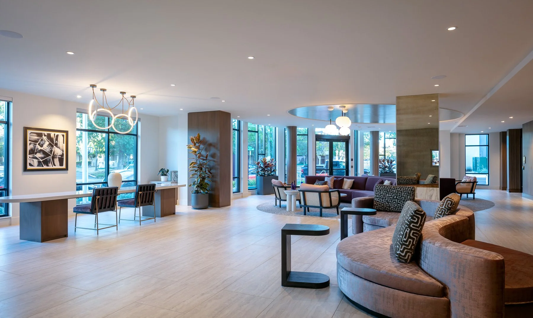 Interior of a modern lobby with curved sofas, chairs, large windows, and contemporary lighting fixtures.