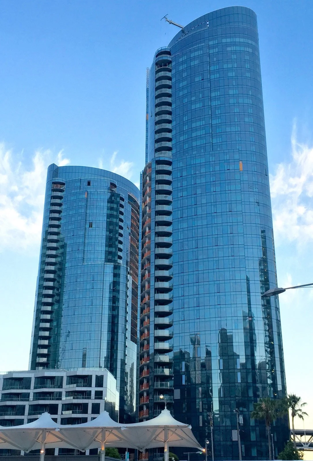 Tall modern skyscraper with glass windows and curved architecture against a blue sky.