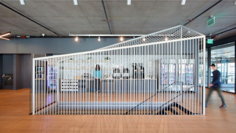 An art installation made of white metal bars creating a geometric structure inside a modern indoor space.