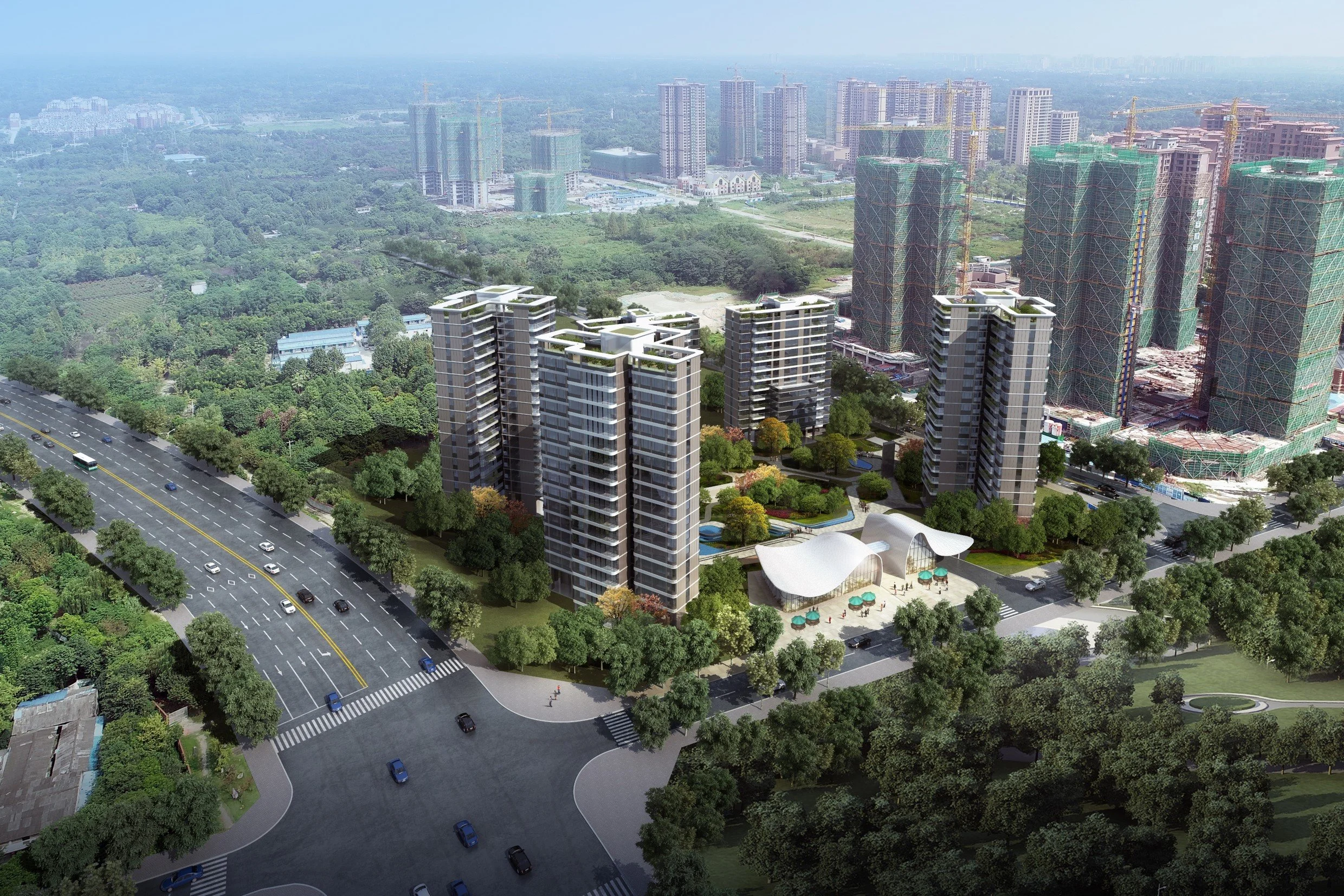 Aerial view of a modern urban development with multiple high-rise buildings, green parks, and a busy road with vehicles in a cityscape.