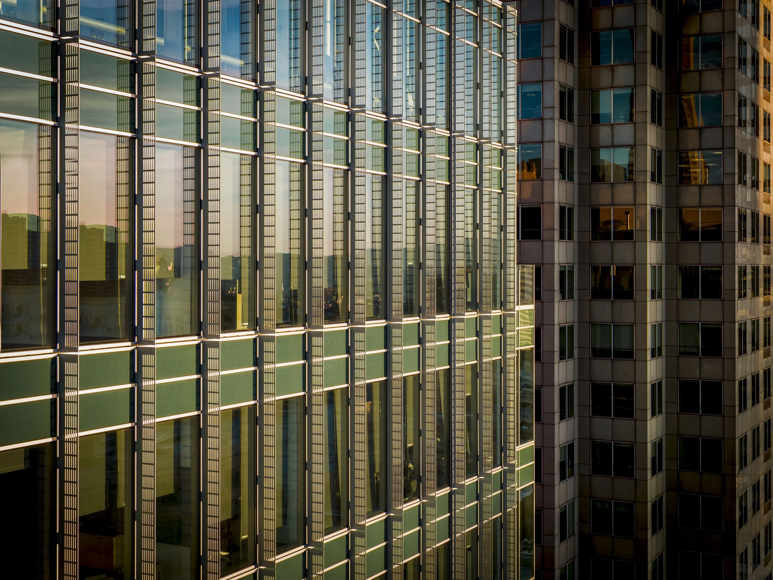 Close-up of a modern skyscraper with glass windows and metal framework reflecting sunlight.