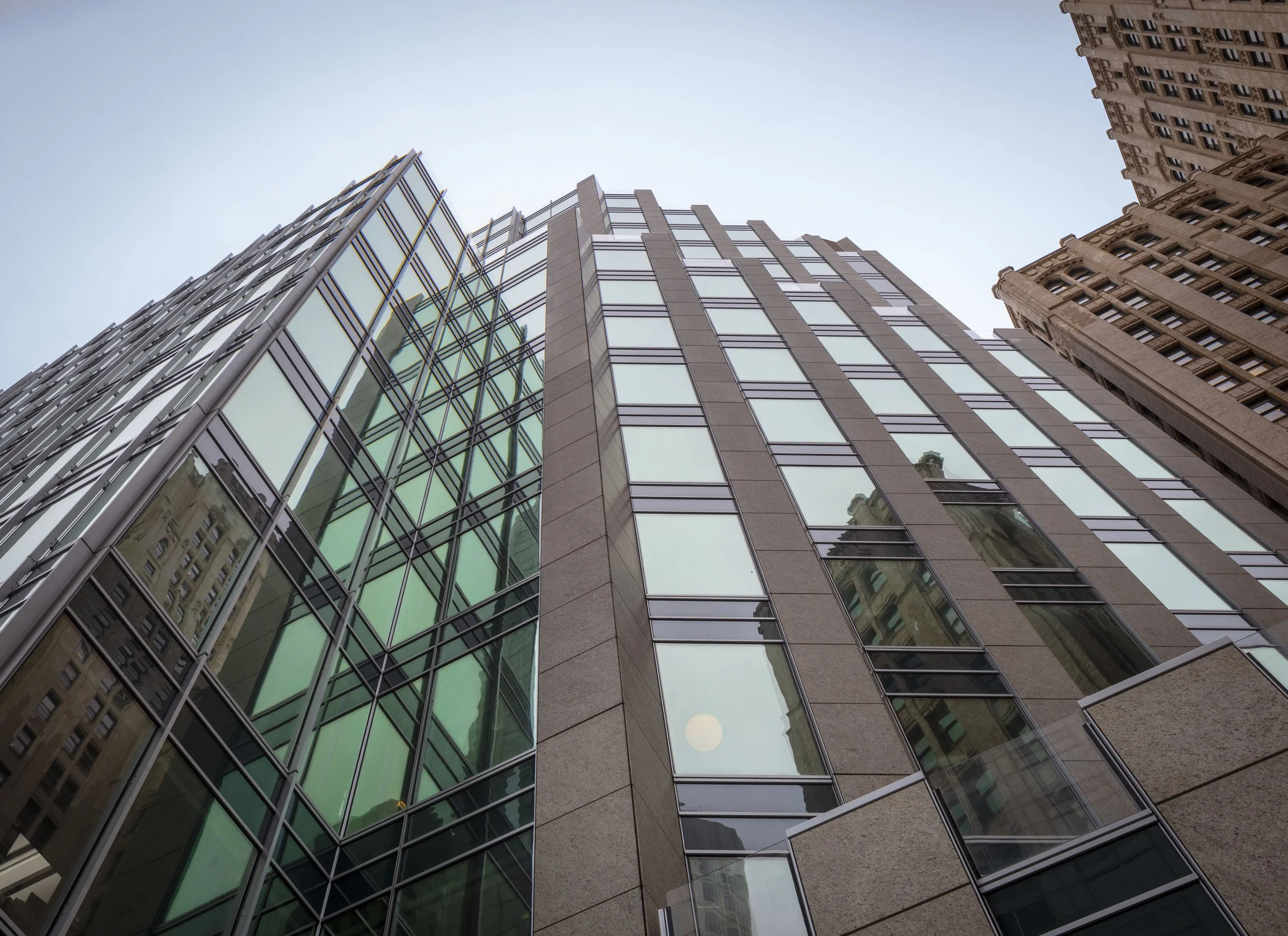 Low-angle view of tall modern glass and stone skyscrapers in an urban cityscape.