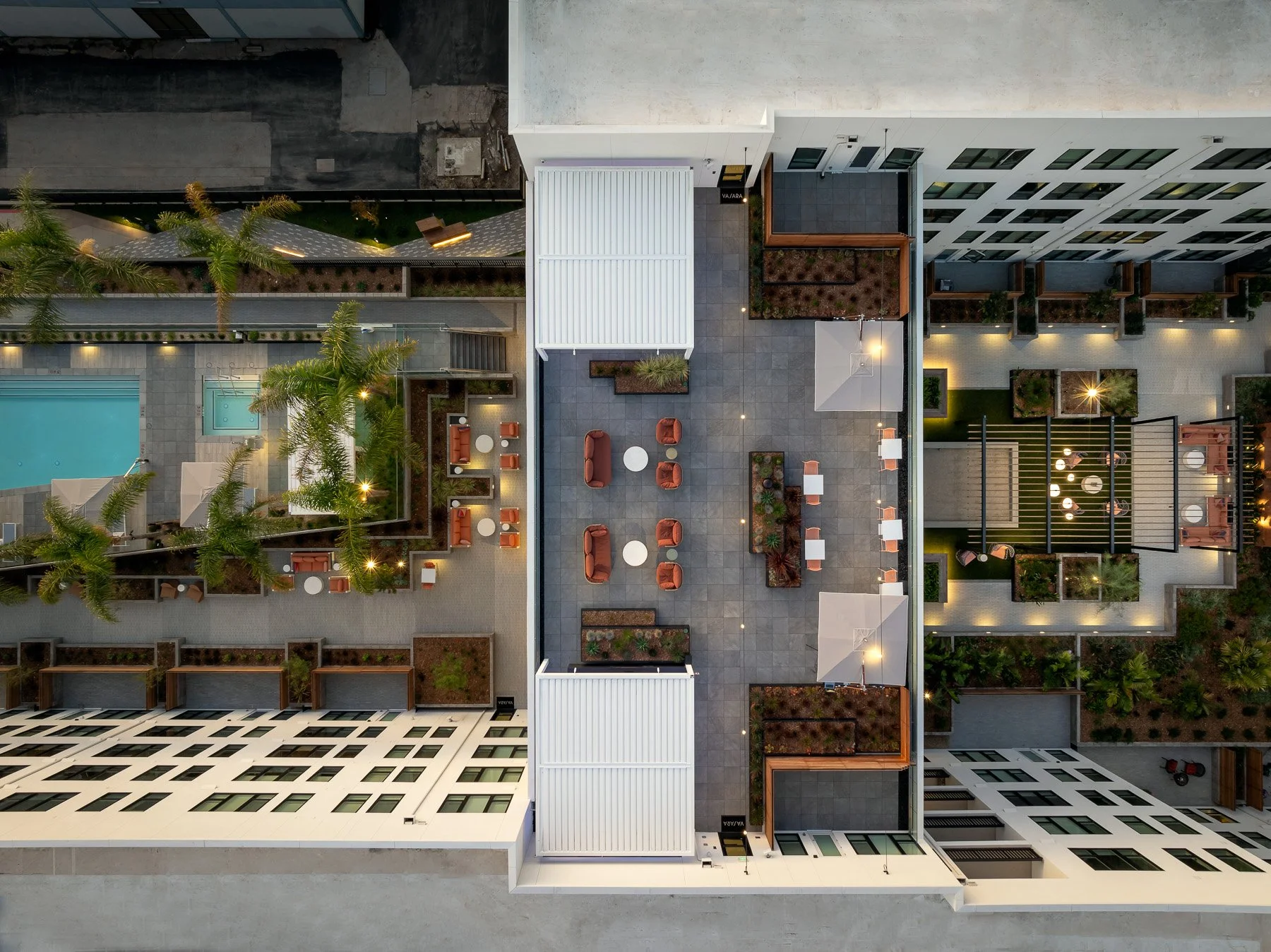 Top-down view of an apartment rooftop with lounge seating, a dining area, small planters, umbrellas, a swimming pool, and surrounding buildings.