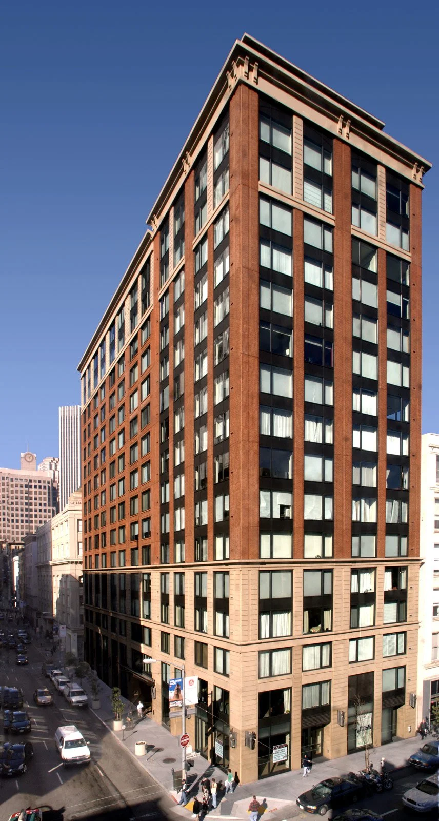 Tall modern brick office building with large glass windows on a city street corner.