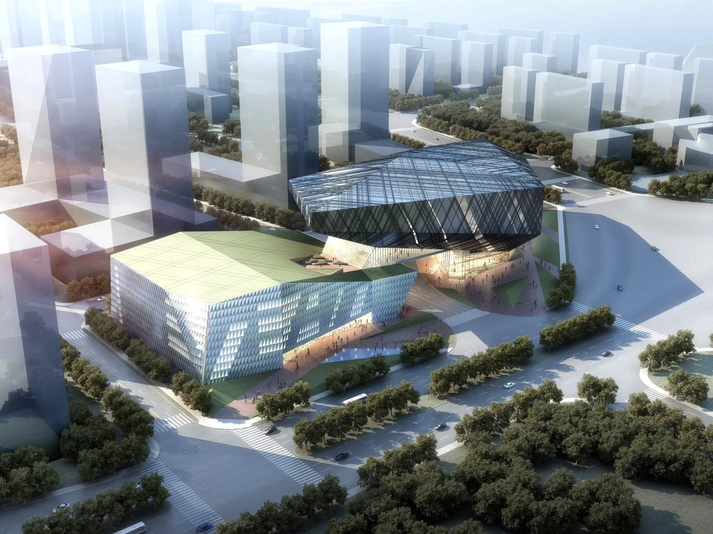 Aerial view of a modern architectural complex with two main buildings: one with a green roof and a geometric facade, and another with a large glass triangular structure, surrounded by trees and roads in an urban setting.