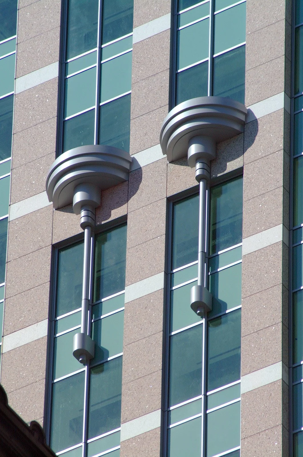 Close-up of a modern building facade with decorative metal elements in front of glass windows.