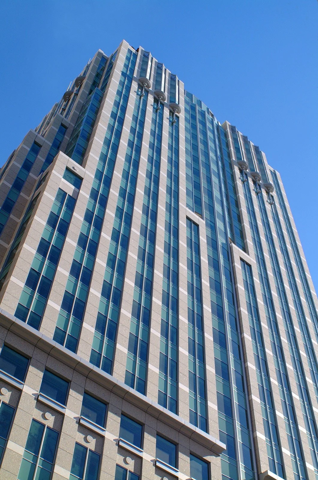 A tall modern glass skyscraper against a clear blue sky.