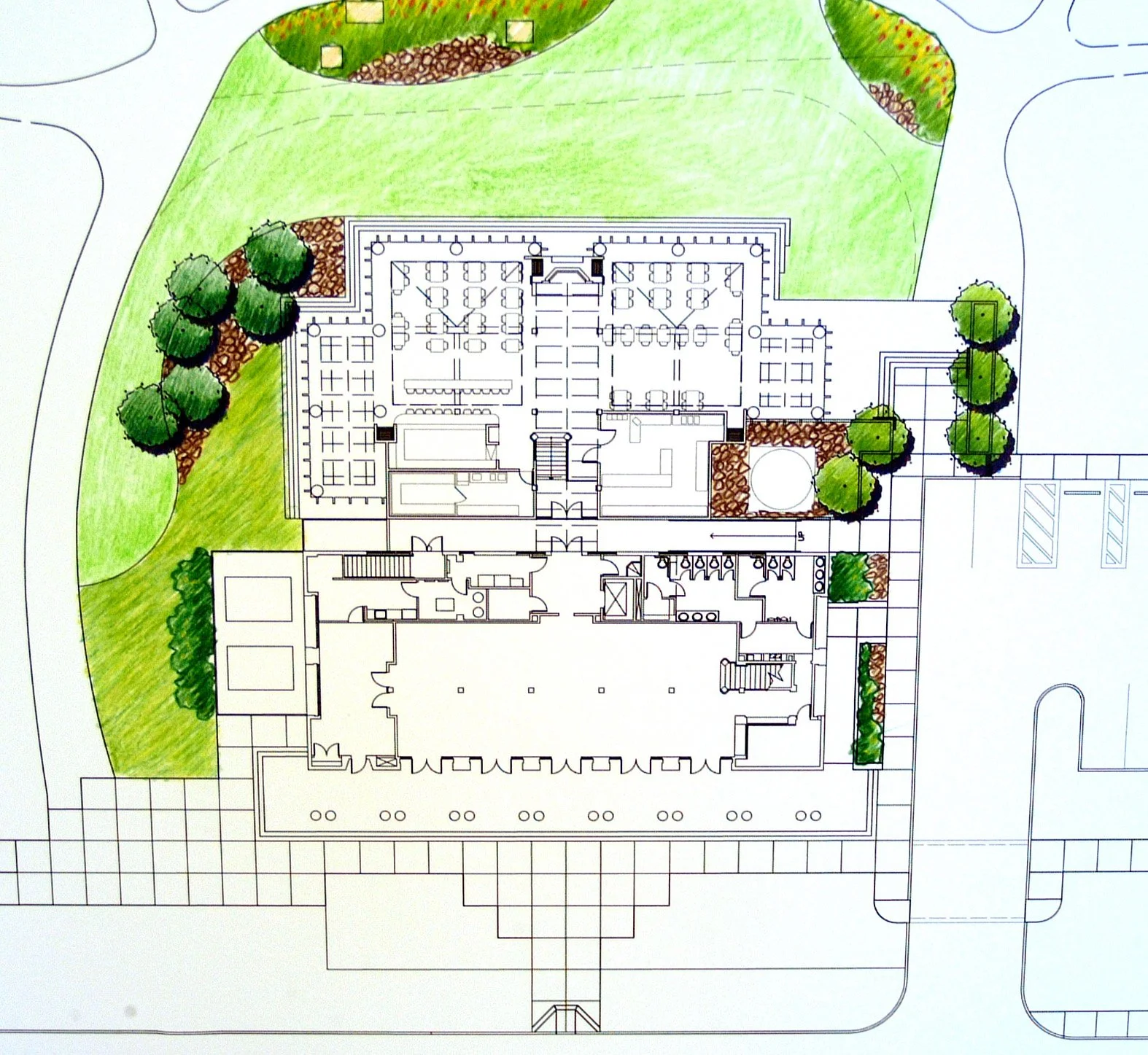 Architectural site plan of a building with surrounding landscaped areas, including trees, walkways, and parking lots.