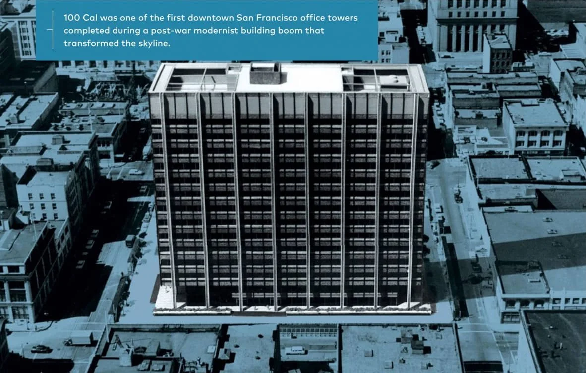 An aerial view of a tall, modern office building in downtown San Francisco. The building has a grid of windows and a flat roof. Surrounding the skyscraper are smaller buildings on a city street.