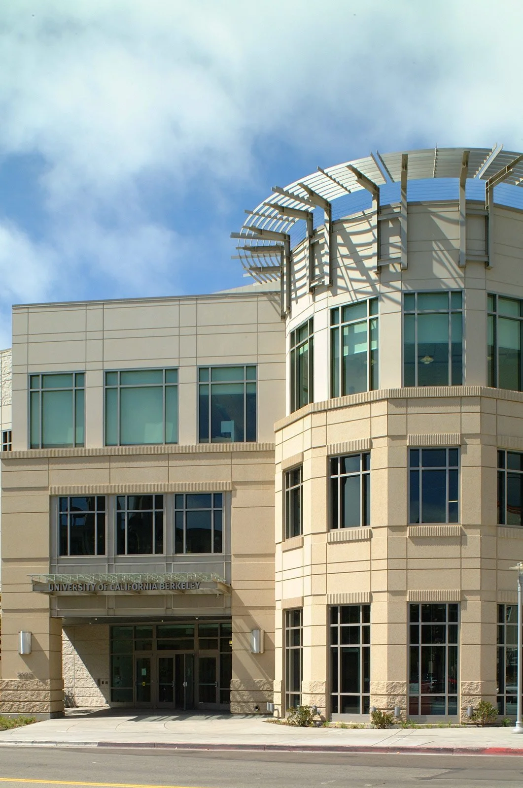Modern multi-story building with large windows and a sign that reads 'University of California Berkeley' above the entrance.