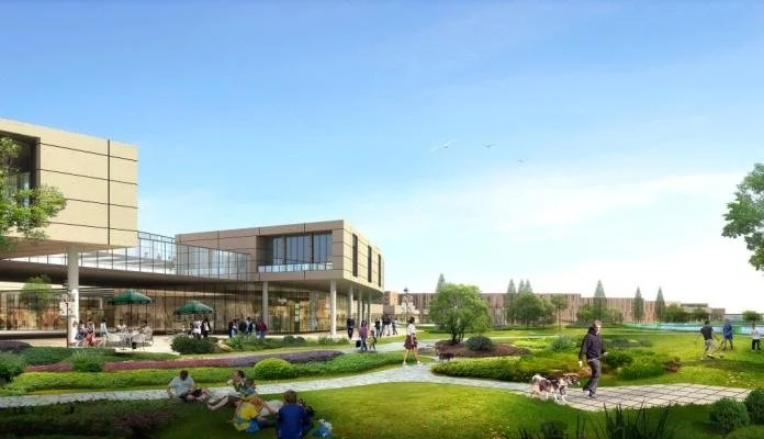 A park with people walking, sitting on the grass, and dogs walking, surrounded by trees, greenery, and modern buildings in the background on a sunny day.