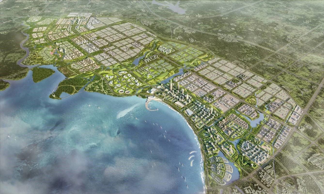 Aerial view of a planned coastal city with greenery, water bodies, parks, residential and commercial areas, and a waterfront with boats and a pier.