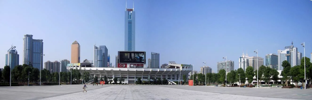 Empty city square with a large screen and numerous tall skyscrapers in the background.