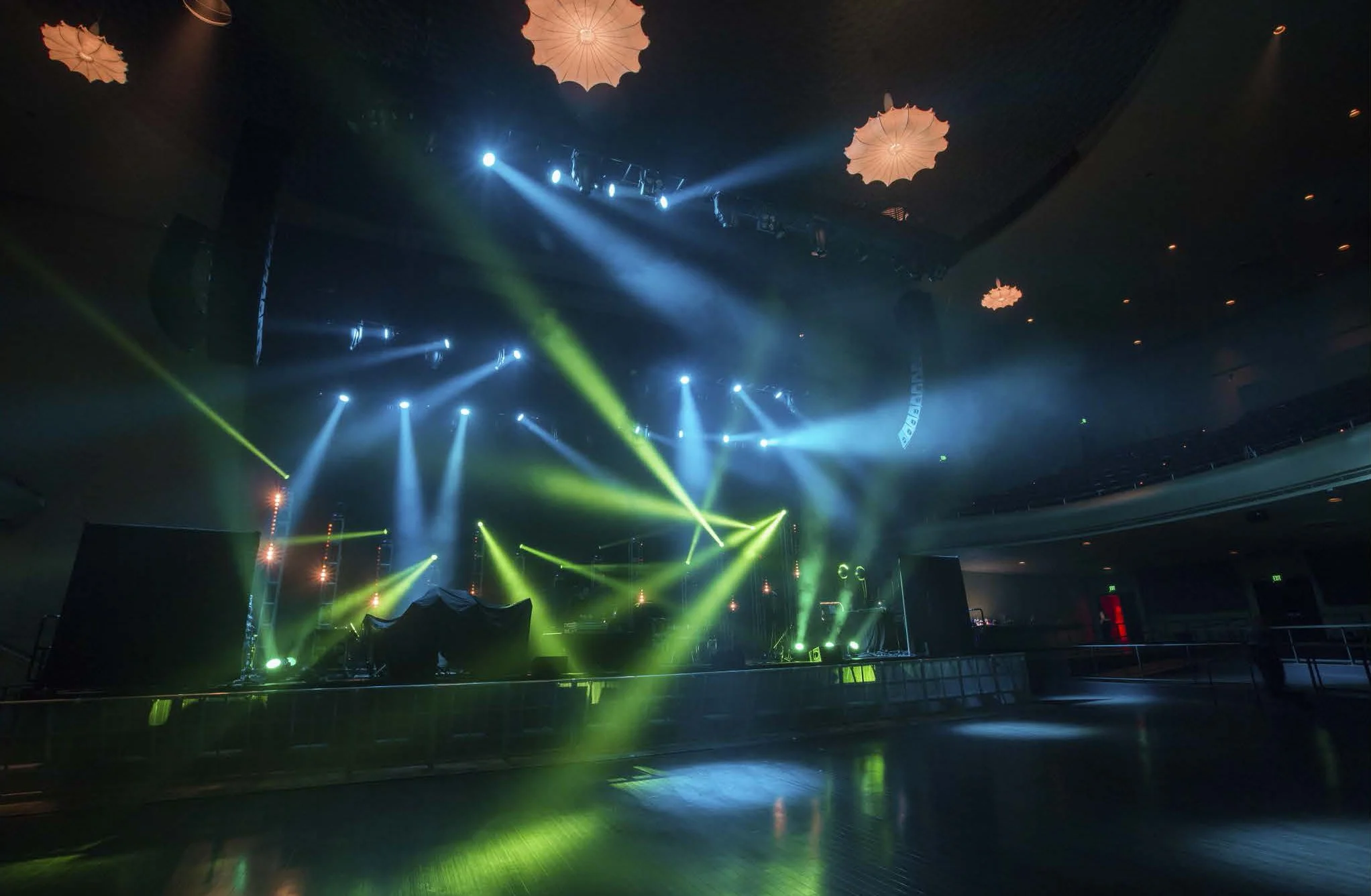 Empty stage with colorful stage lights and fog, ready for a concert or performance in a large venue.