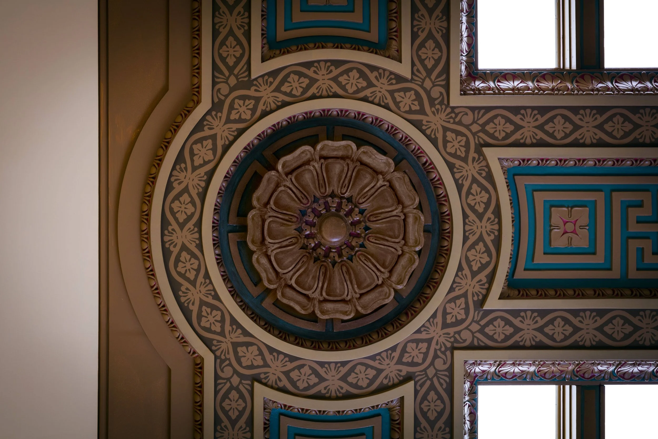 Ceiling with ornate decorative patterns, a central circular ceiling medallion with floral motifs, and patterned ceiling sections with windows.