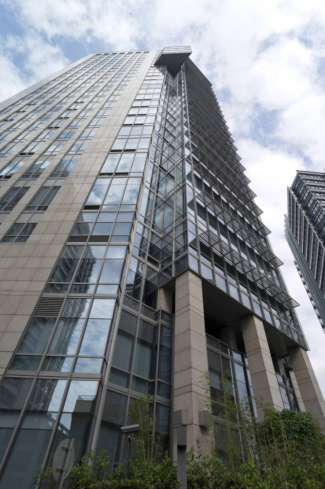 Smart high-rise office building with glass windows and metal accents, reflecting the partly cloudy sky.