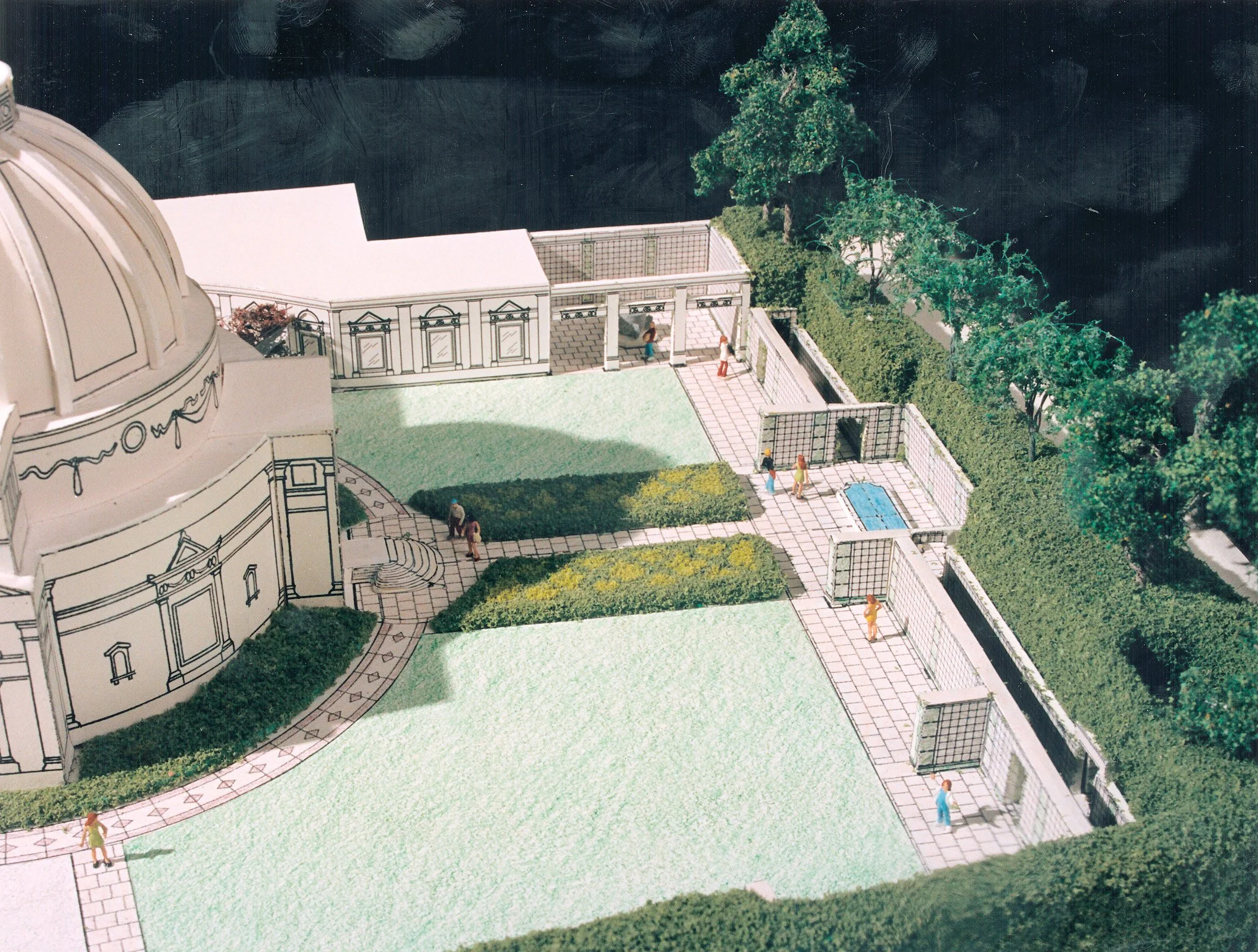 Architectural model of a large building with a domed roof, outdoor pools, and a landscaped outdoor area with pathways, bushes, and trees.