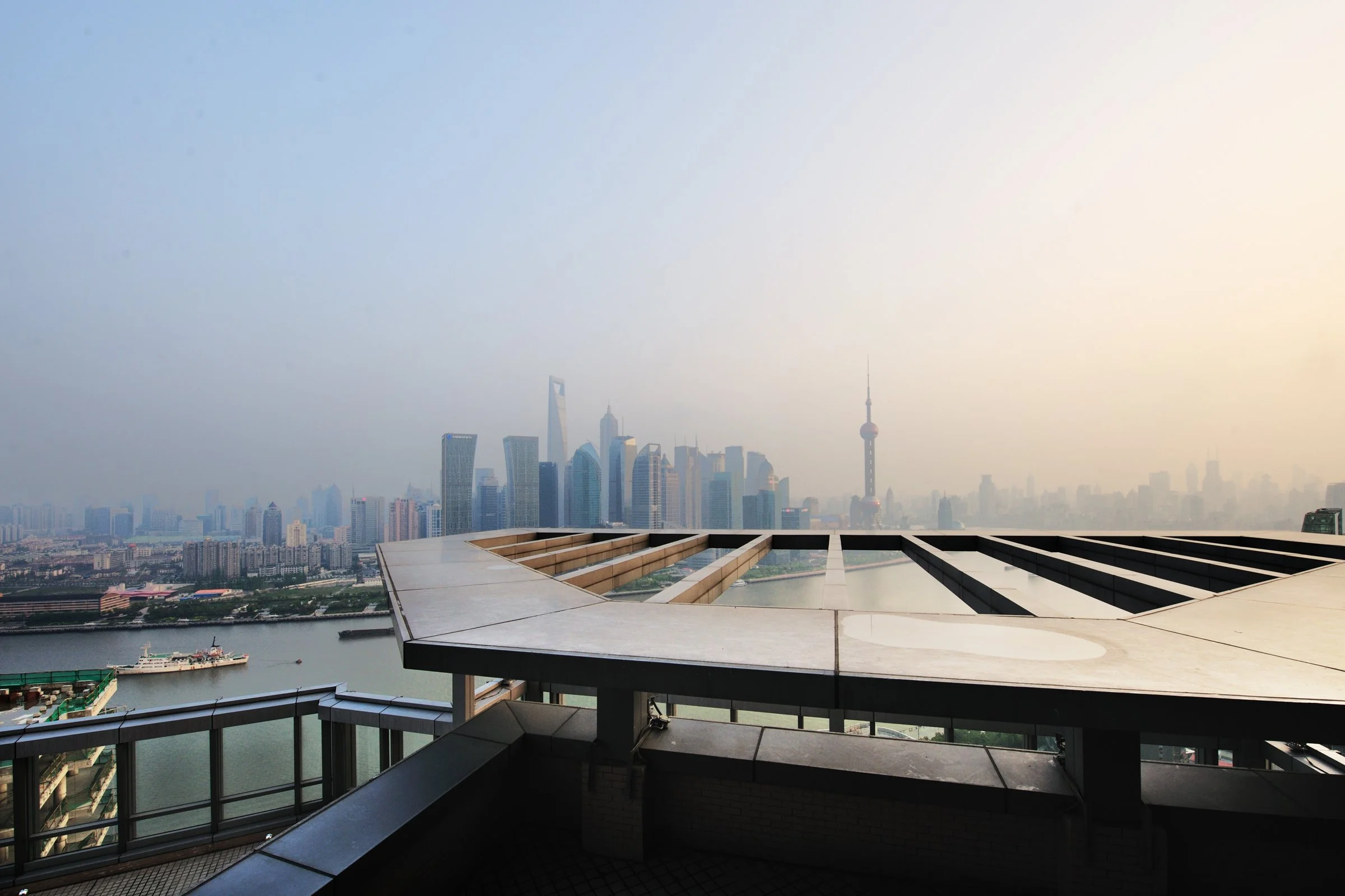 View of Shanghai skyline with tall skyscrapers and the Oriental Pearl Tower from a rooftop terrace.