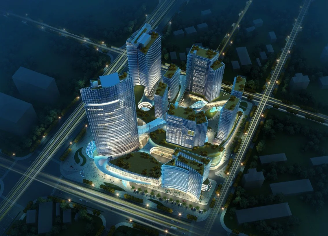 Nighttime aerial view of a modern city complex with tall illuminated skyscrapers, roads with vehicle lights, connecting bridges, and green spaces.