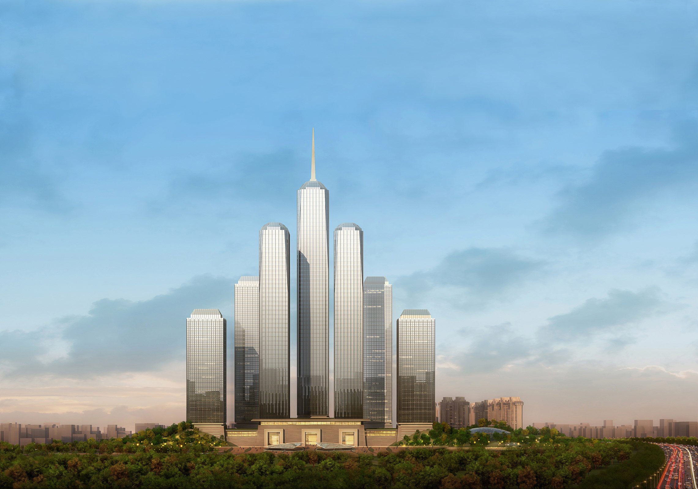 A tall modern skyscraper with multiple towers rises above a green landscape, set against a partly cloudy sky during daytime.