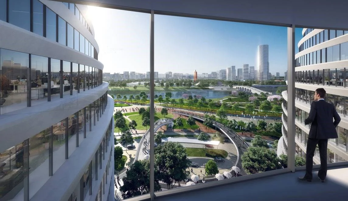 A man in a suit standing on a balcony overlooking a city park with a pond, trees, and a waterway, with city buildings in the background.