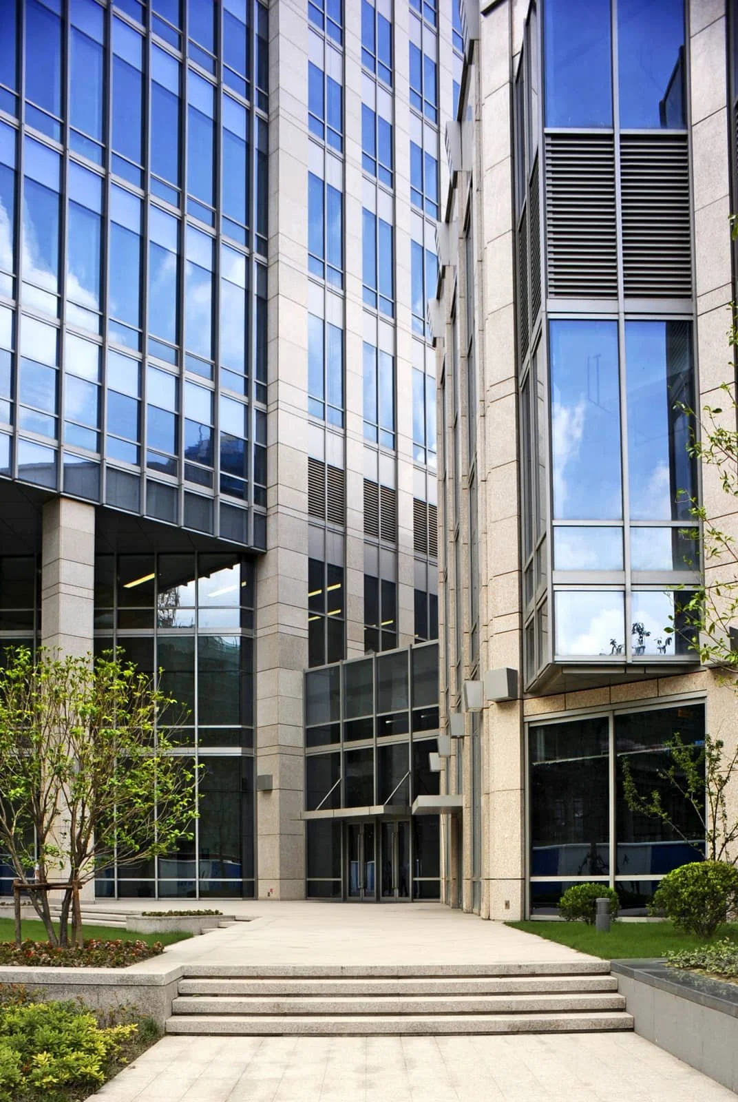 Modern office building with glass windows and landscaped entrance.