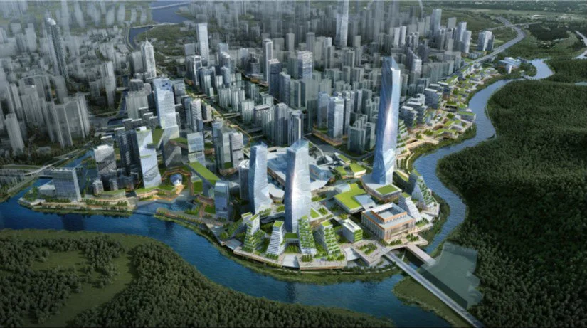 Aerial view of a modern city with many tall skyscrapers, surrounded by a river and green forests, with a bridge crossing the river.