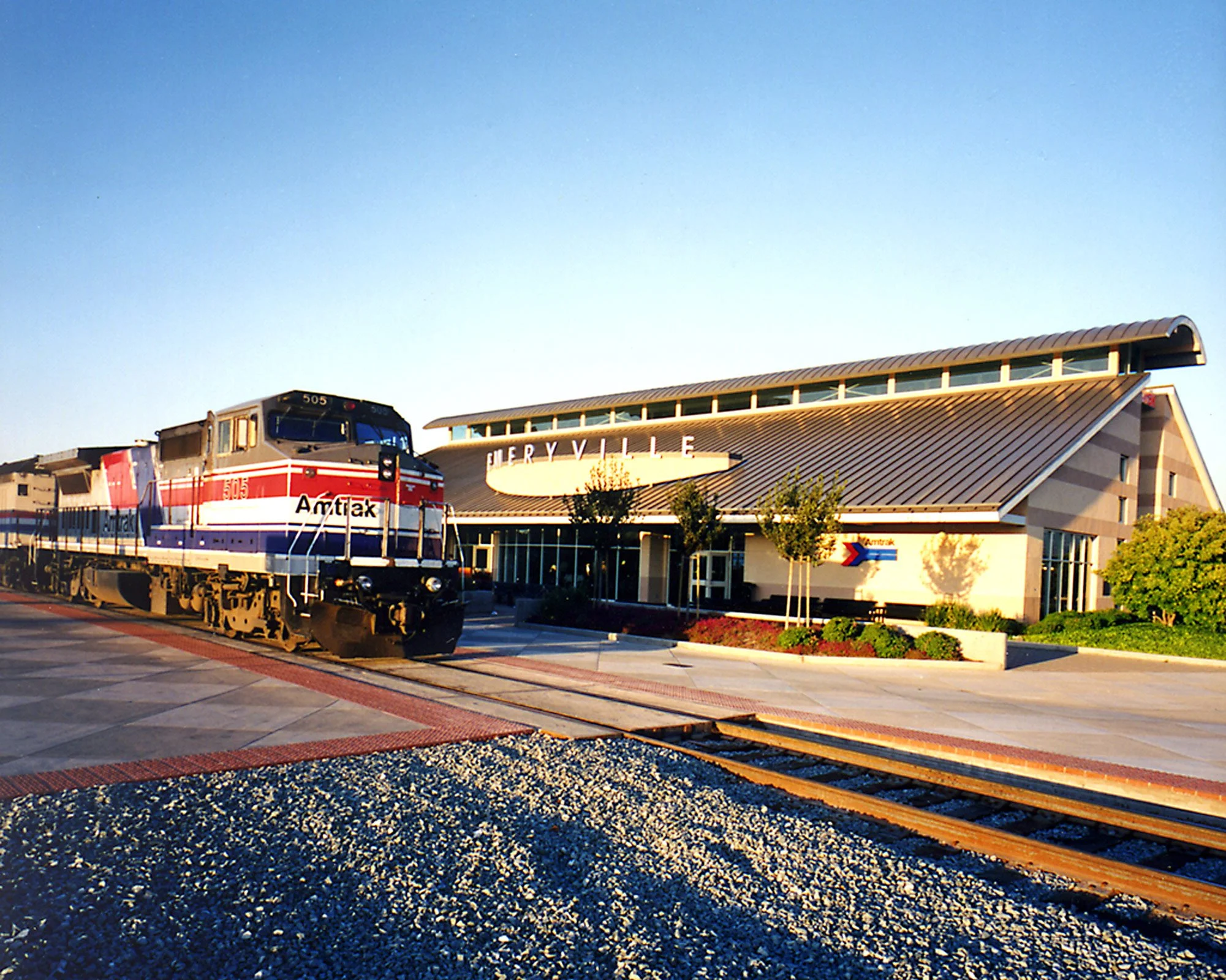 Amtrak train parked outside a modern service center with a large sign reading 'ServiceYard' in the background.