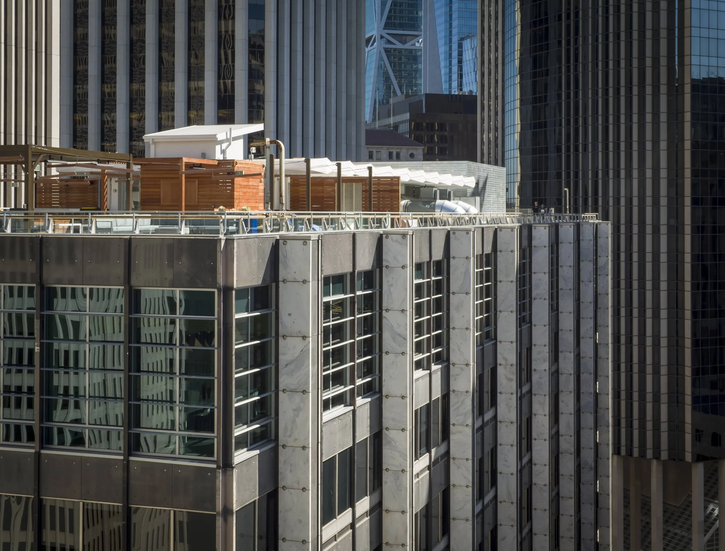 View of the rooftops of modern high-rise buildings in a city with glass windows and metal details.