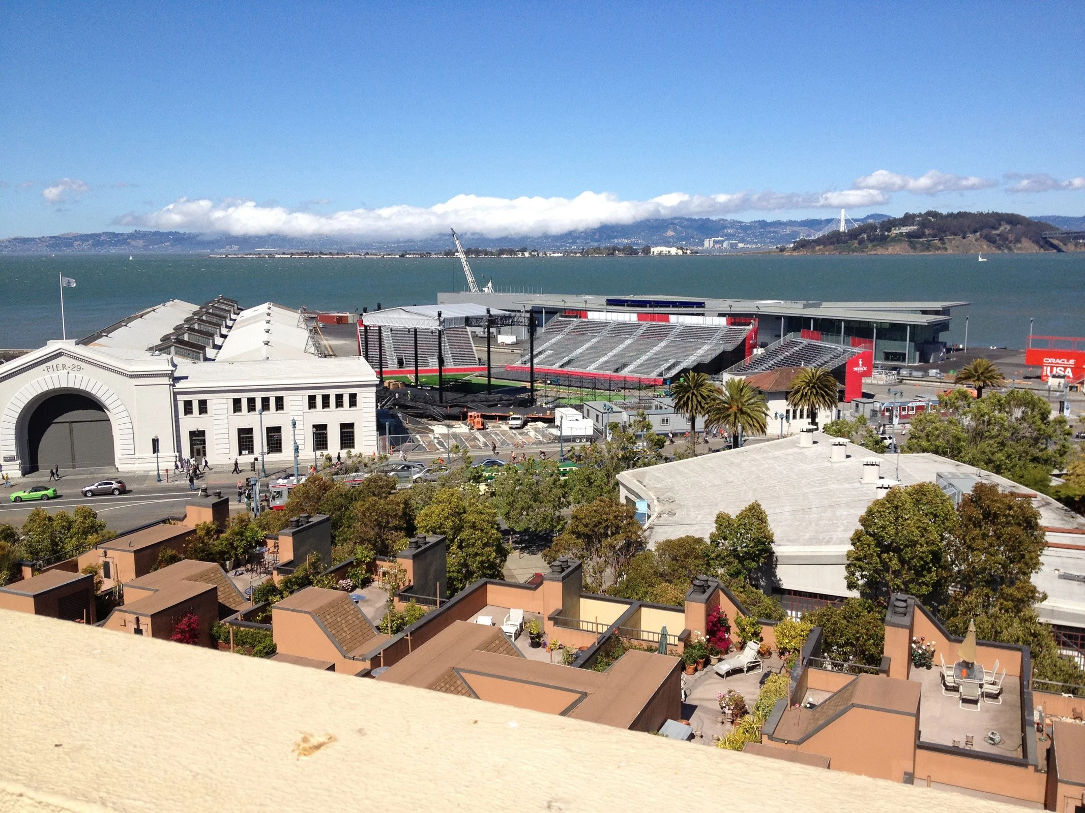 Aerial view of Oracle Park in San Francisco, with the waterfront, hills in the background, and palm trees in the foreground.