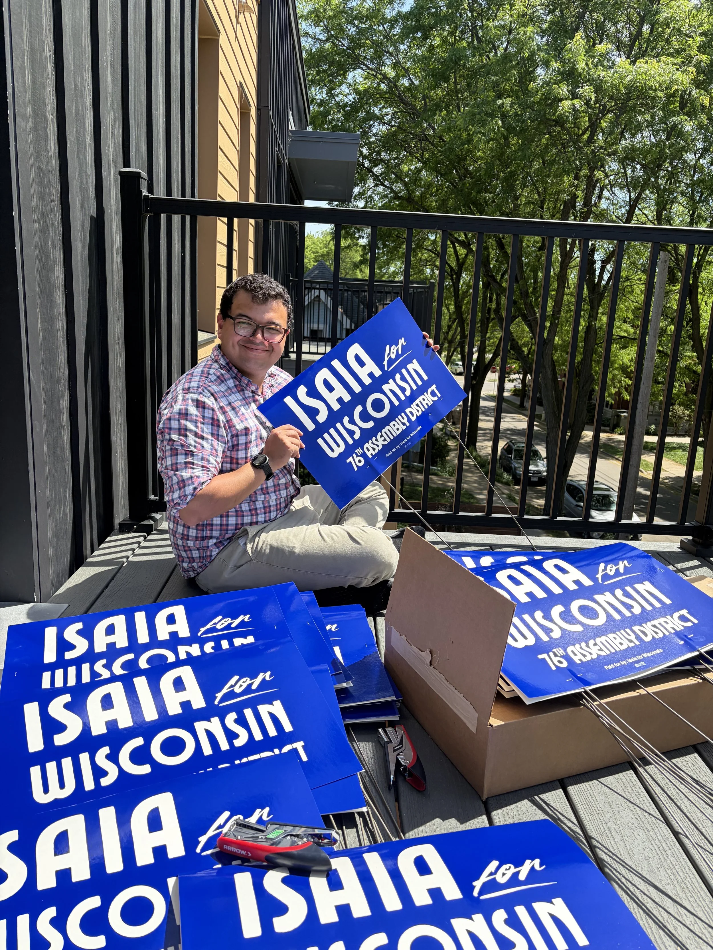 Isaia holding an Isaia for Wisconsin Yard Sign on a porch