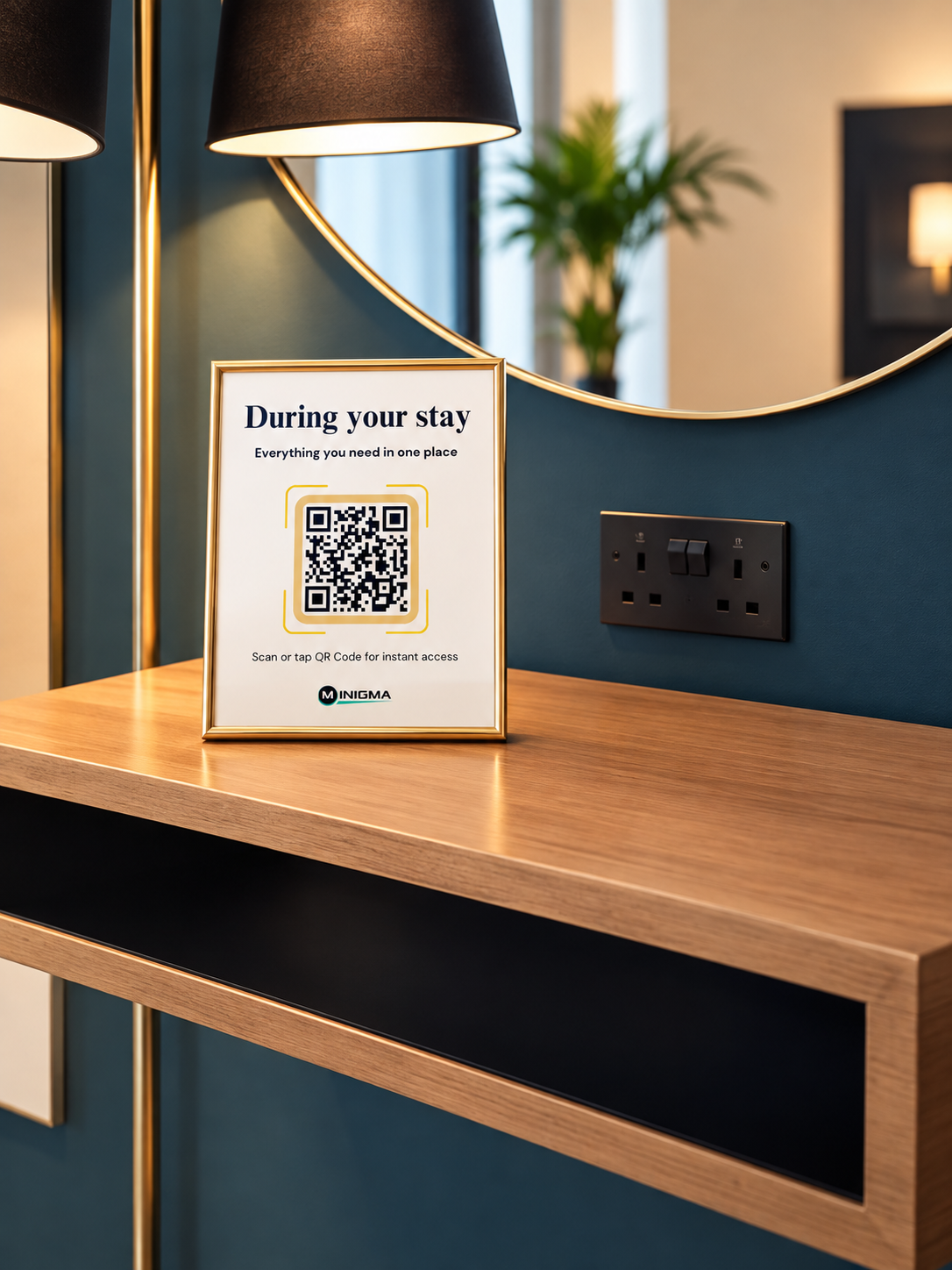 A framed sign on a wooden table with a QR code for instant access, next to a black electrical outlet, against a teal wall with a round mirror and a lamp in the background.