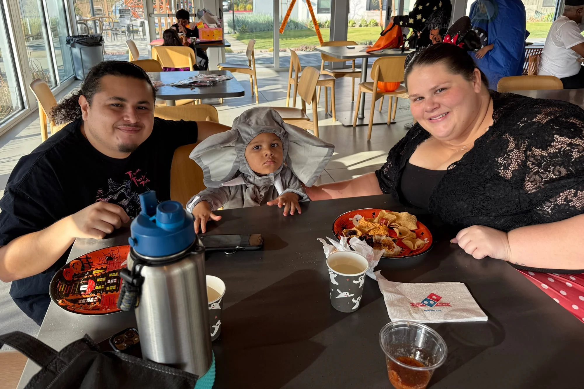 A family sitting at a table at an event, enjoying a meal together in an open dining space.