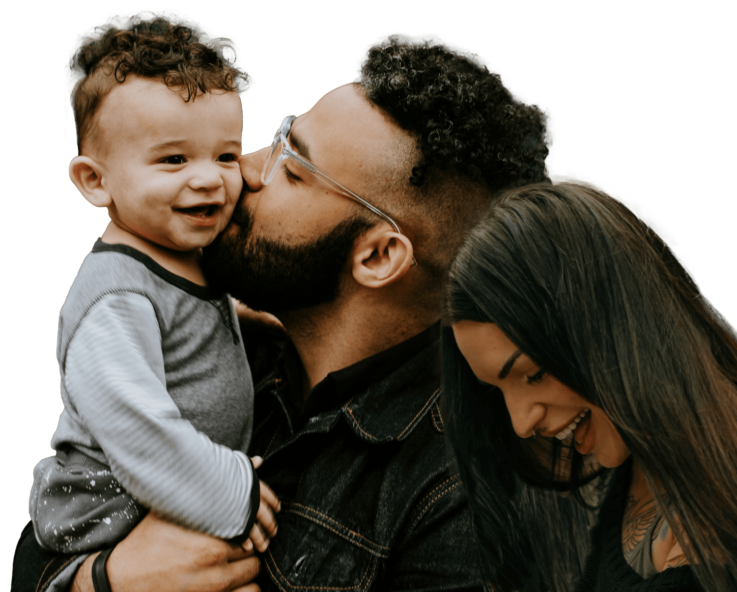 A family of three, including a father, mother, and young son, sharing a joyful moment; the father is kissing his son on the cheek, the son is smiling, and the mother is smiling and looking down.