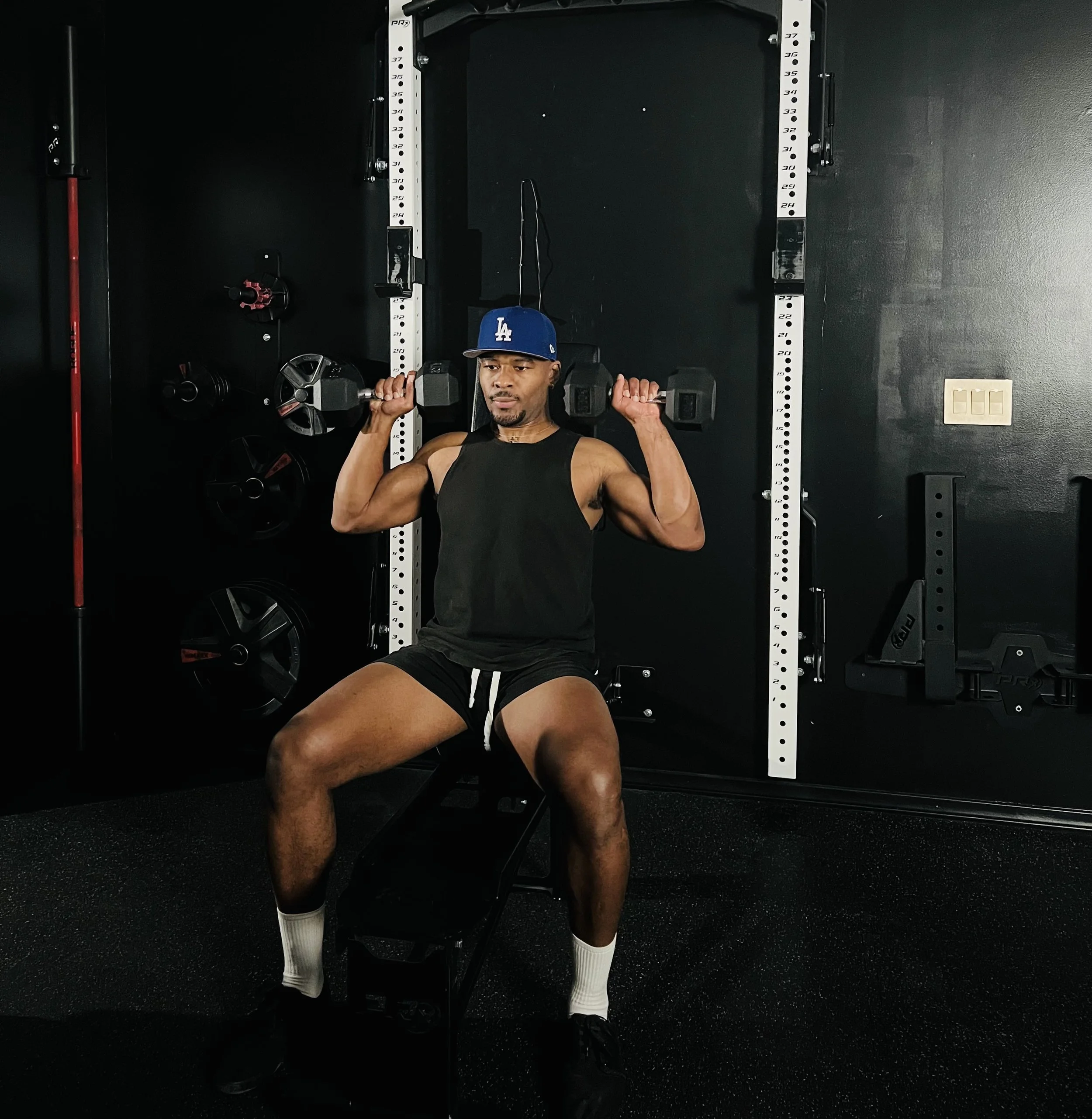 A man lifting dumbbells while sitting on a workout bench in a gym.