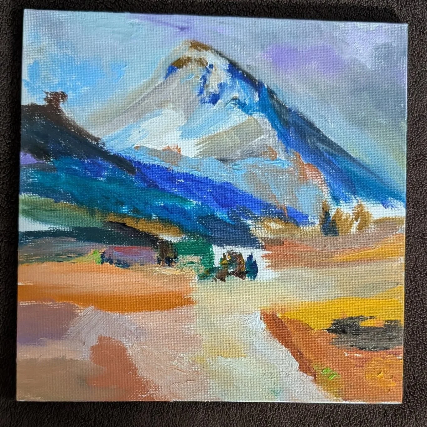 A colorful watercolor painting of a mountain with snow-capped peaks, rolling hills, and a sunset sky.