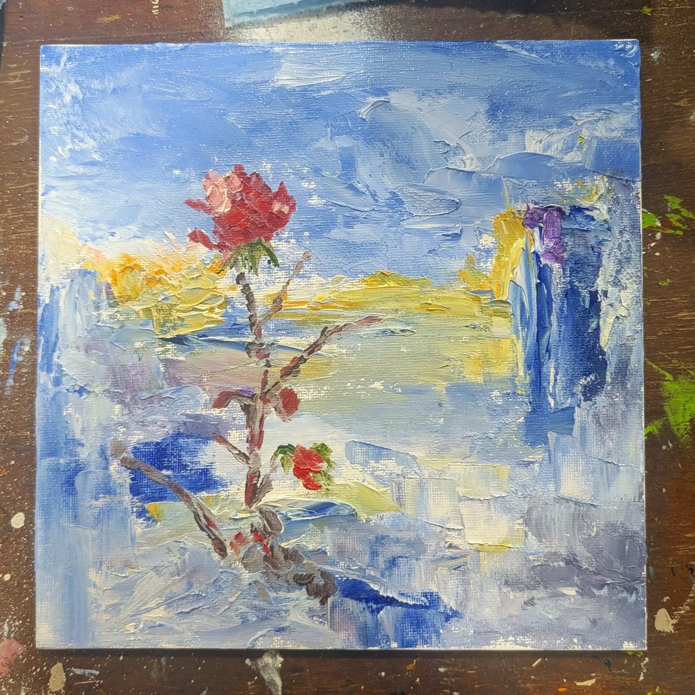 Abstract painting of a landscape with a cloudy sky, distant hills, a branch with red and green leaves, and water reflections.