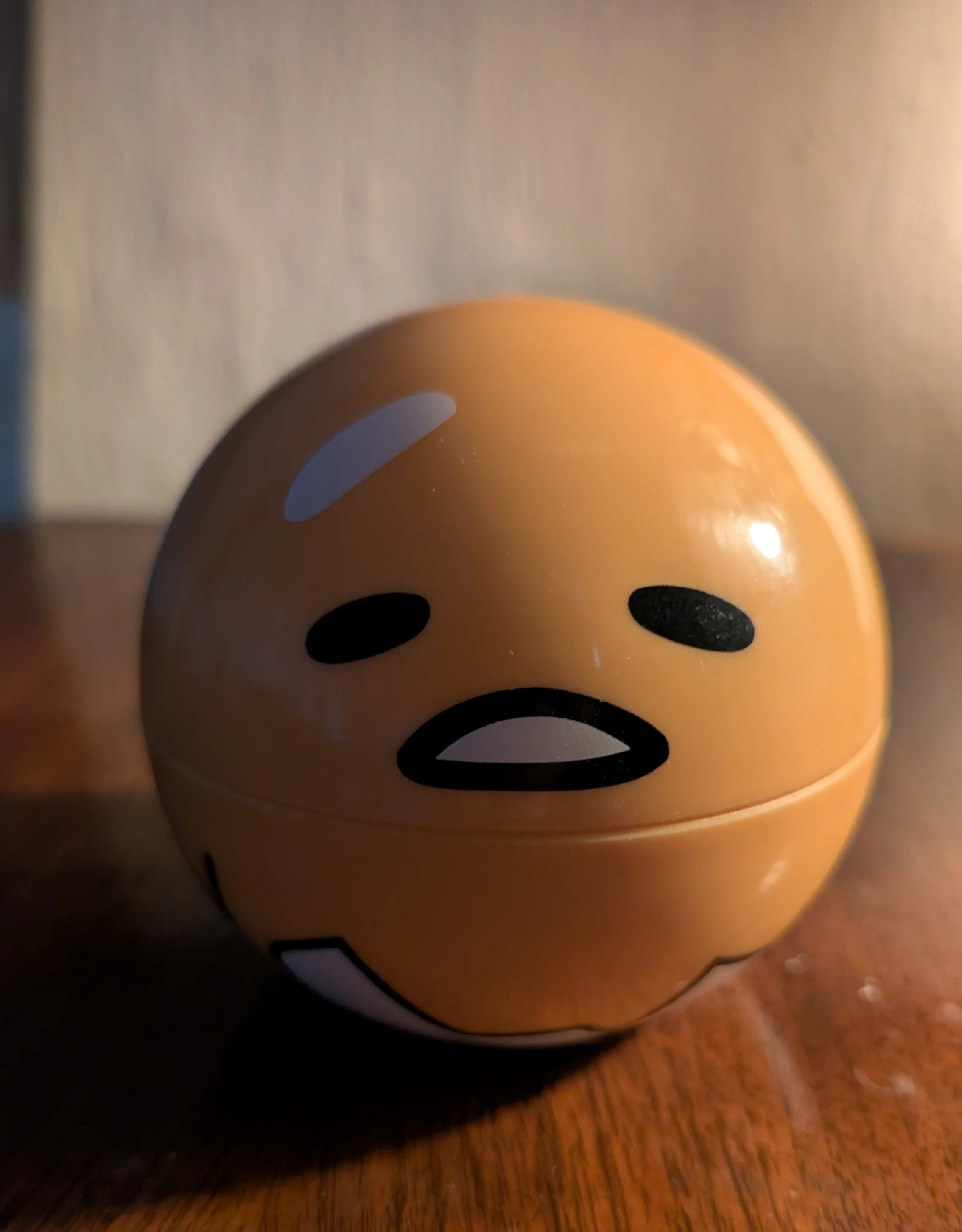 Close-up of a ceramic emoji mug with a smiling face, placed on a wooden surface.