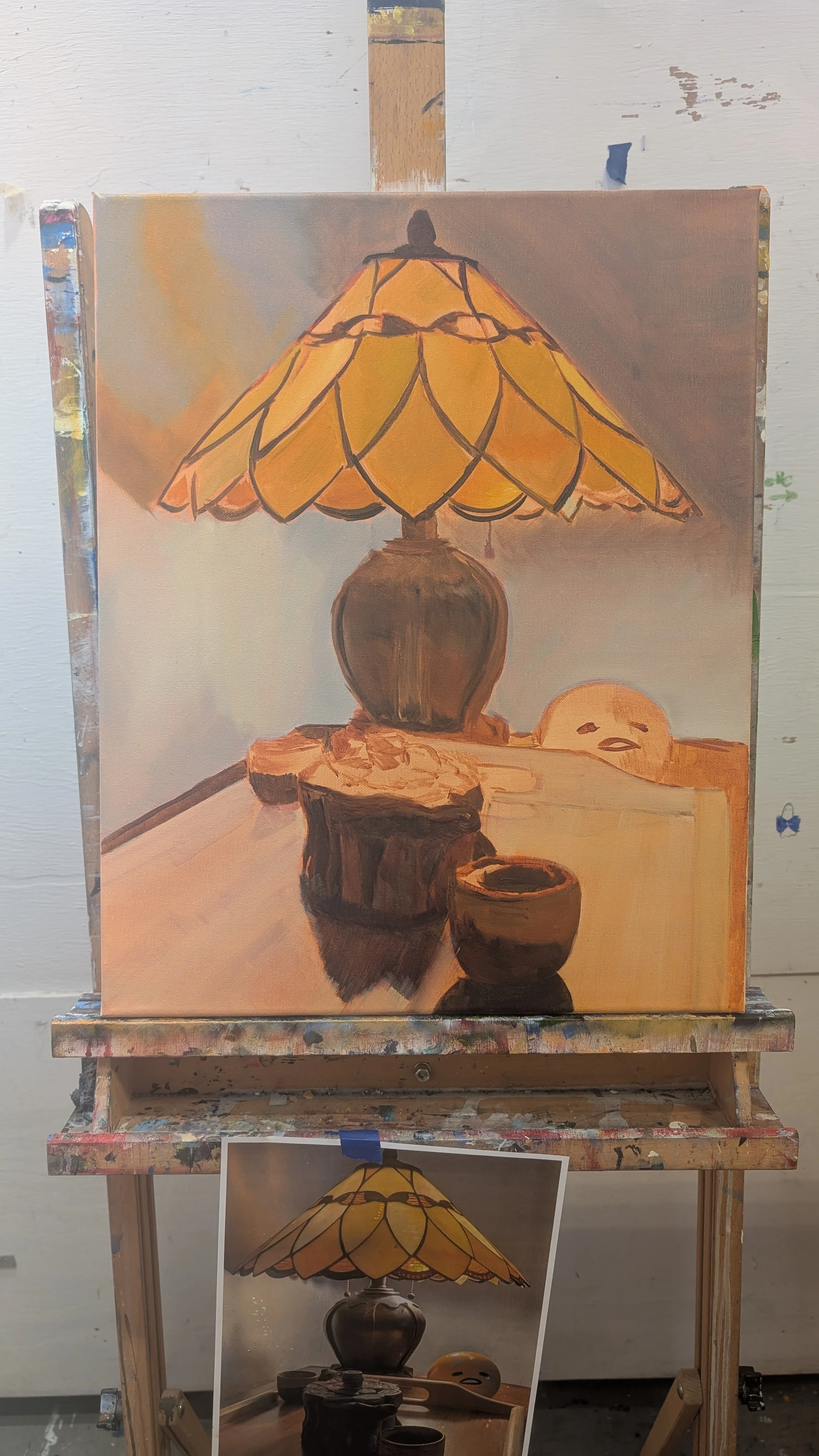 Painting of a table lamp with a yellow stained glass shade, objects on the table, and a light-colored wall in the background.