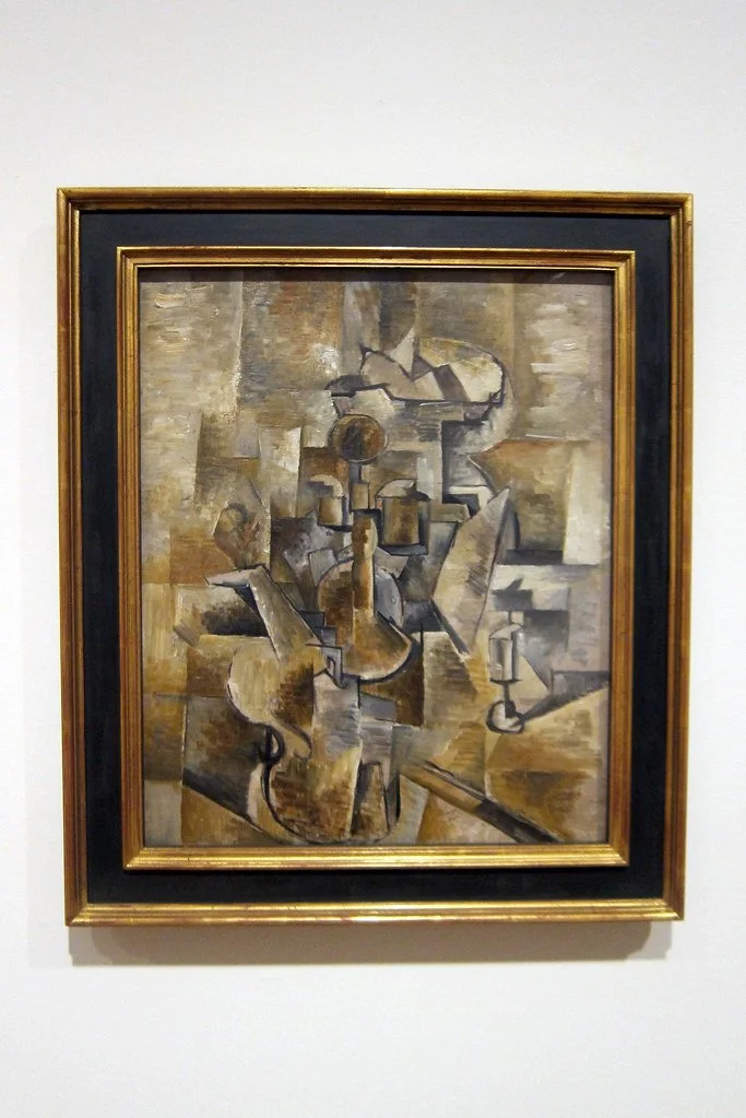 Early Cubist painting by Georges Braque featuring a fragmented violin and candlestick rendered through geometric forms, muted earth tones, and multiple overlapping perspectives.