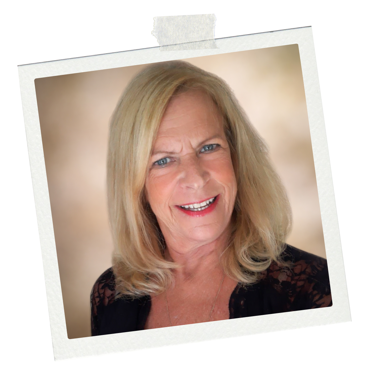 Portrait of a smiling middle-aged woman with blonde hair, blue eyes, wearing a black lace top, against a blurred neutral background.