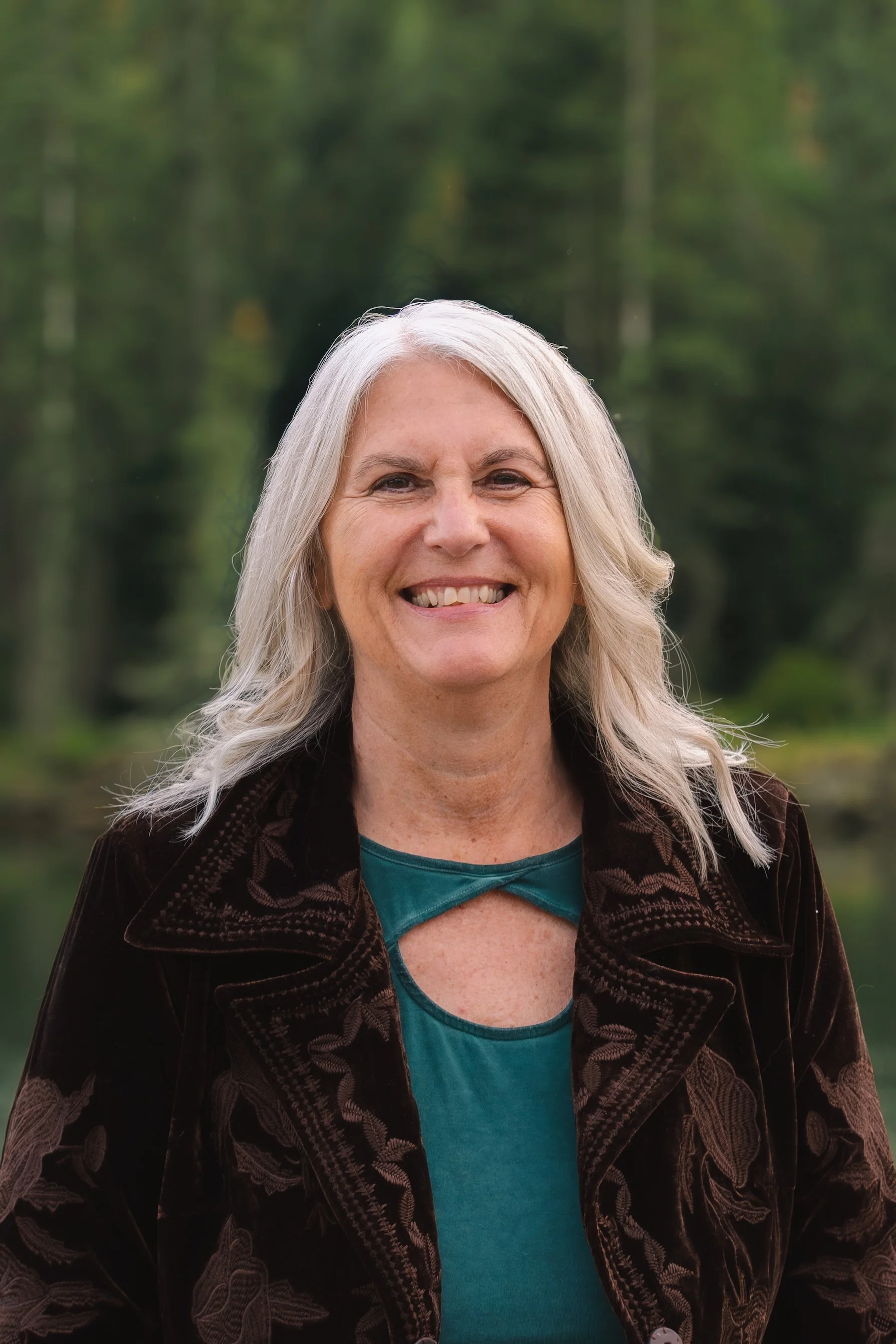 A smiling woman with outdoors with a forest background.