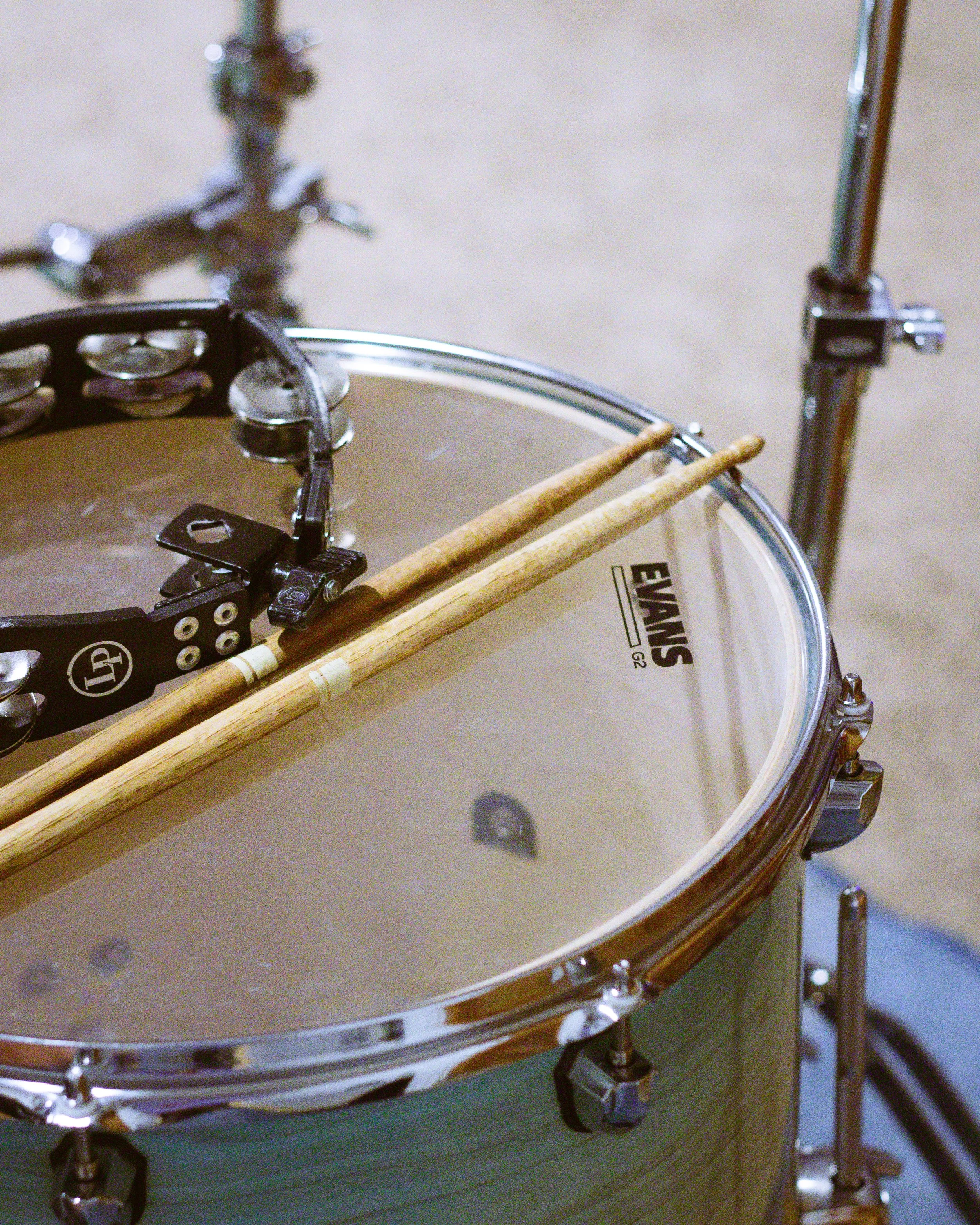 Close-up of a drum set with wooden drumsticks resting on the drumhead.