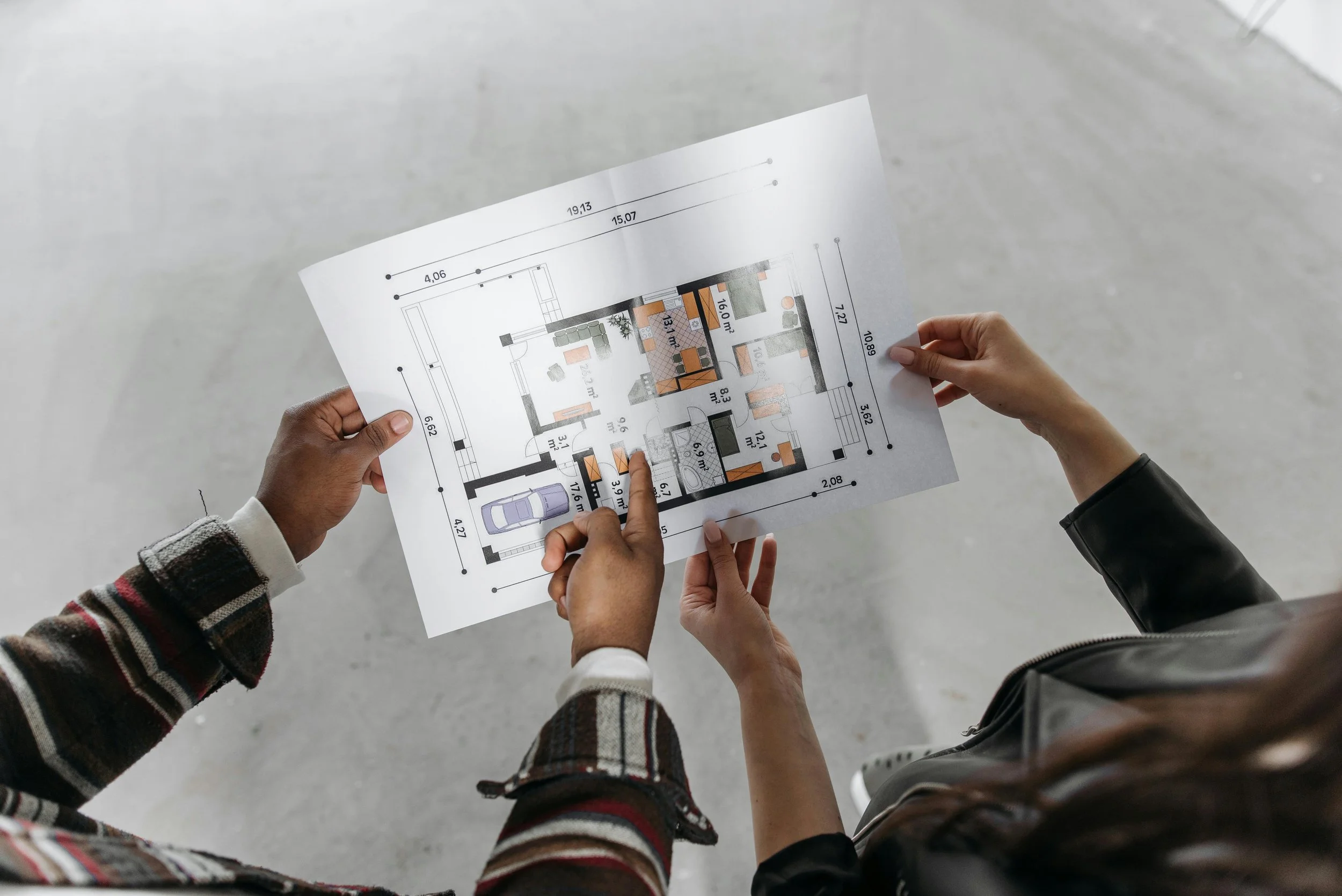 People holding a floor plan or architectural blueprint indoors.