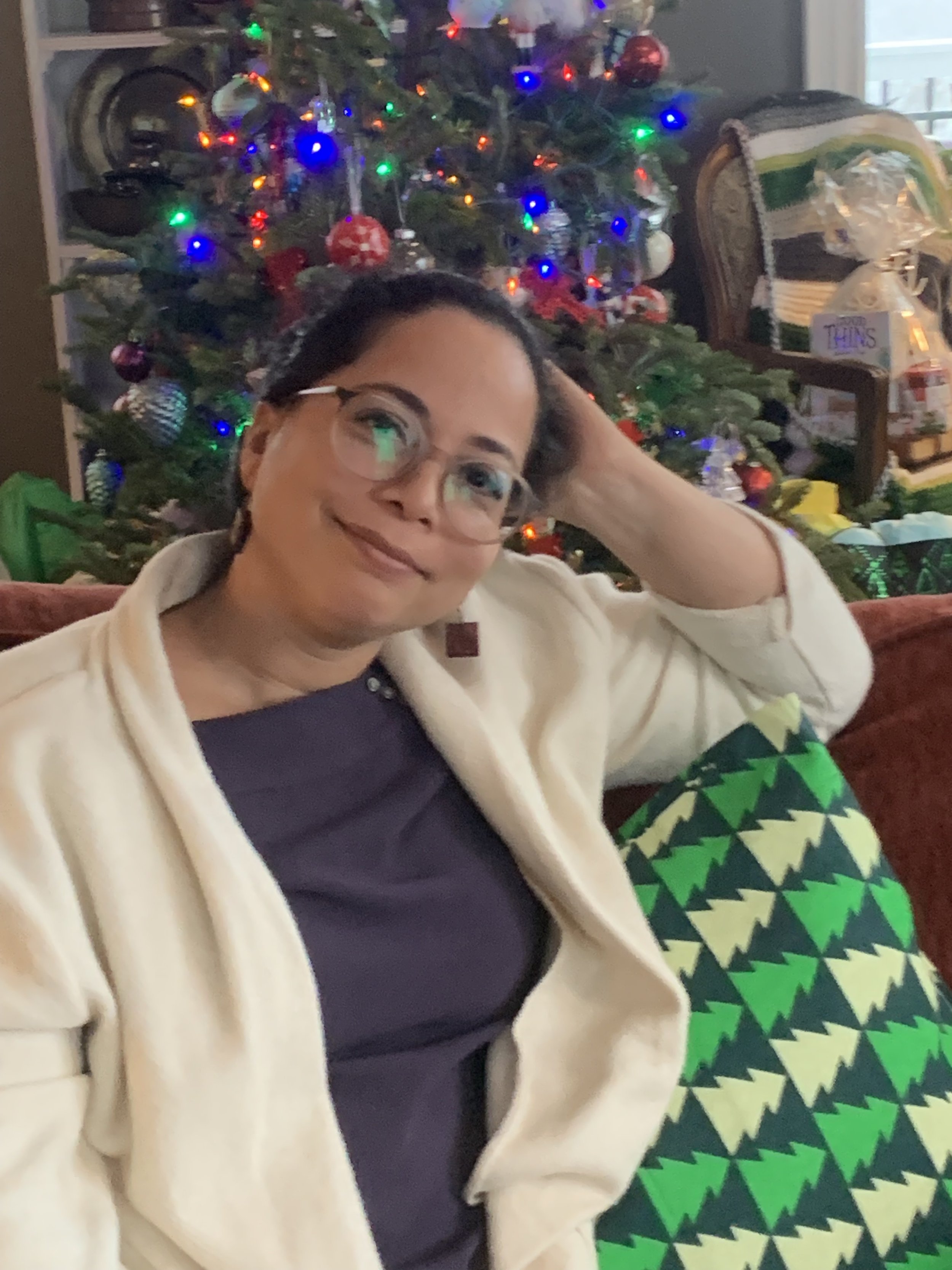 picture of woman sitting in front of a Christmas tree looking half sad