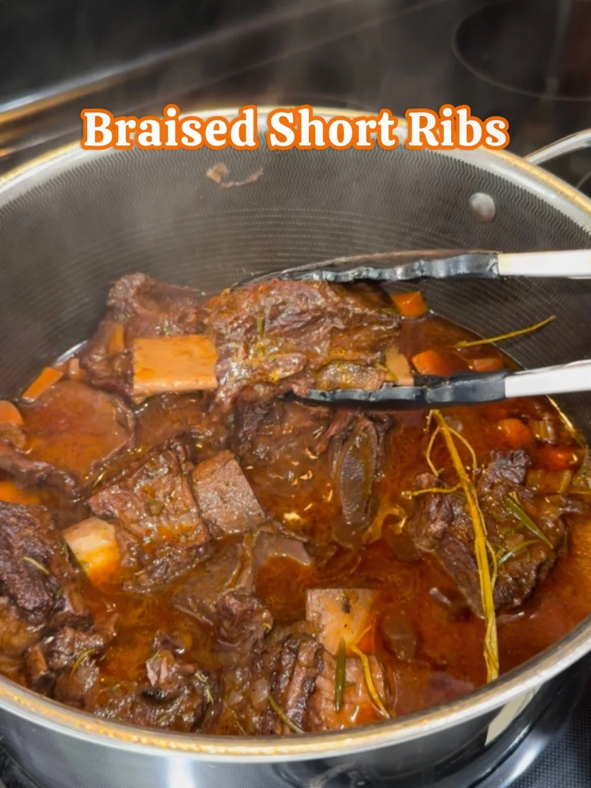 A pot of braised short ribs in a rich sauce with carrots and herbs.