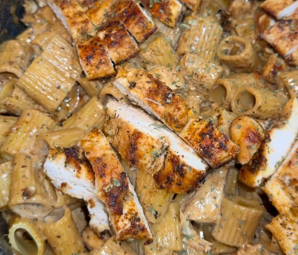 Cooked pasta with creamy sauce and sliced grilled chicken on top.